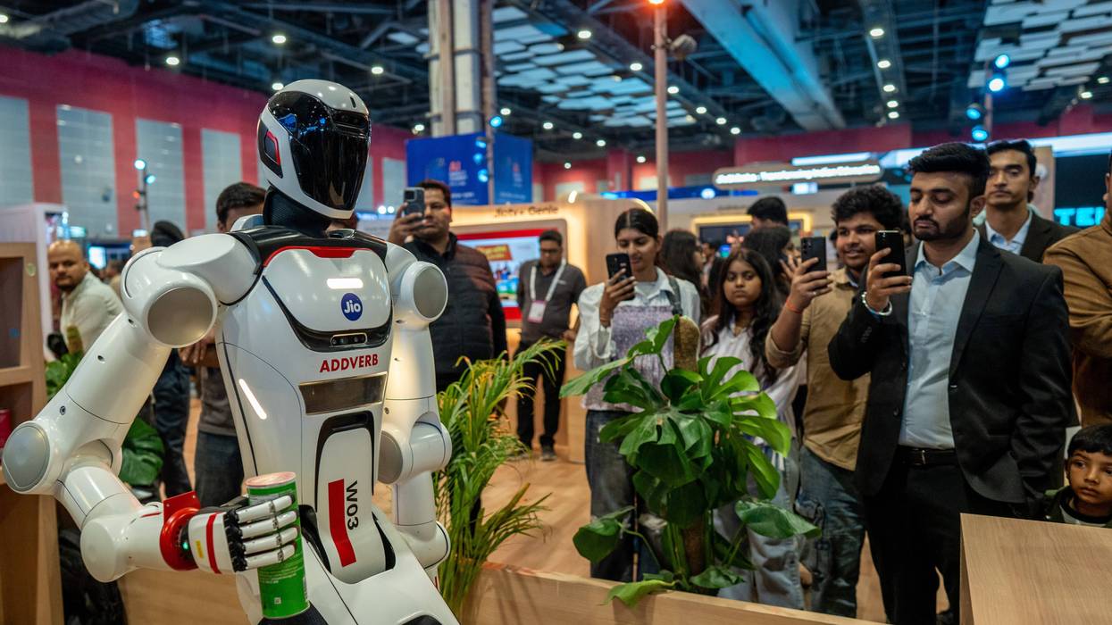 People take photos and videos of a robot at the AI Impact Summit in New Delhi