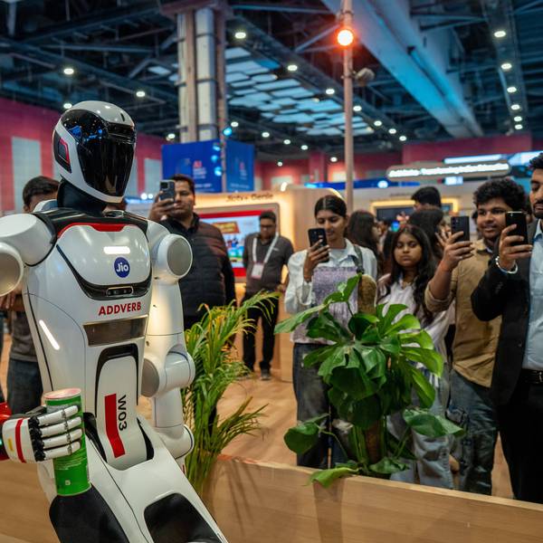 People take photos and videos of a robot at the AI Impact Summit in New Delhi