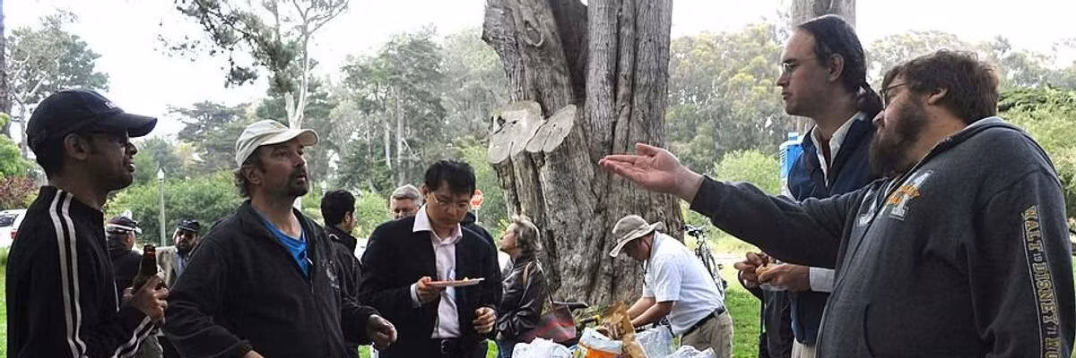 People talk over a picnic table.