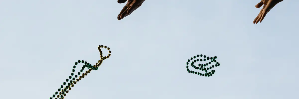 People toss Mardi Gras beads.