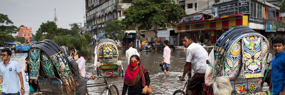 People wade through floodwater in Chittagong, Bangladesh on July 26, 2017.