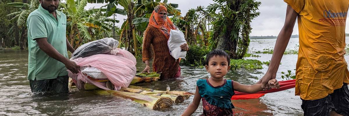 People wade through floodwaters in Feni, Bangladesh