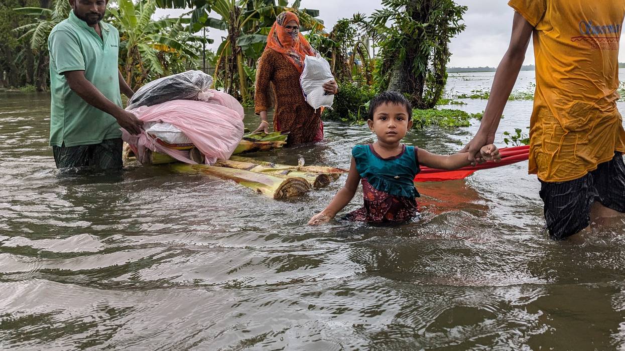 People wade through floodwaters in Feni, Bangladesh