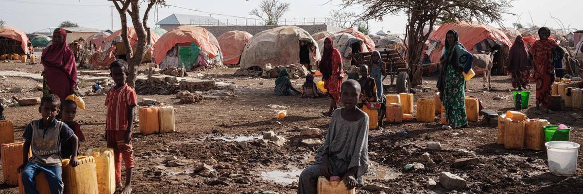 People wait for water with containers at a camp for internally displaced persons in Baidoa, Somalia, on February 13, 2022.