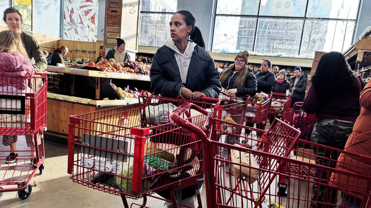 People wait in line in a grocery store.