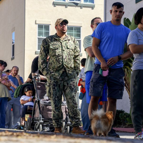 People wait in line to receive free food from volunteers with a food bank