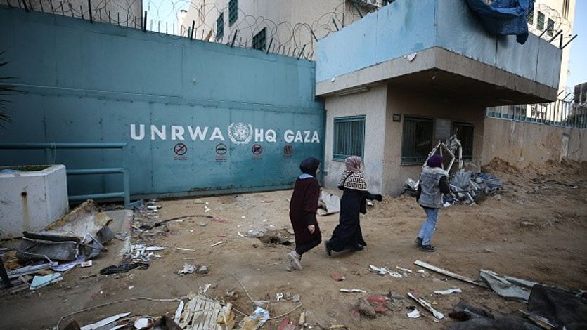 People walk past the headquarters of the United Nations Relief and Works Agency for Palestine Refugees in the Near East