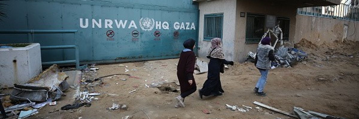 People walk past the headquarters of the United Nations Relief and Works Agency for Palestine Refugees in the Near East