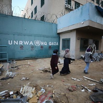 People walk past the headquarters of the United Nations Relief and Works Agency for Palestine Refugees in the Near East