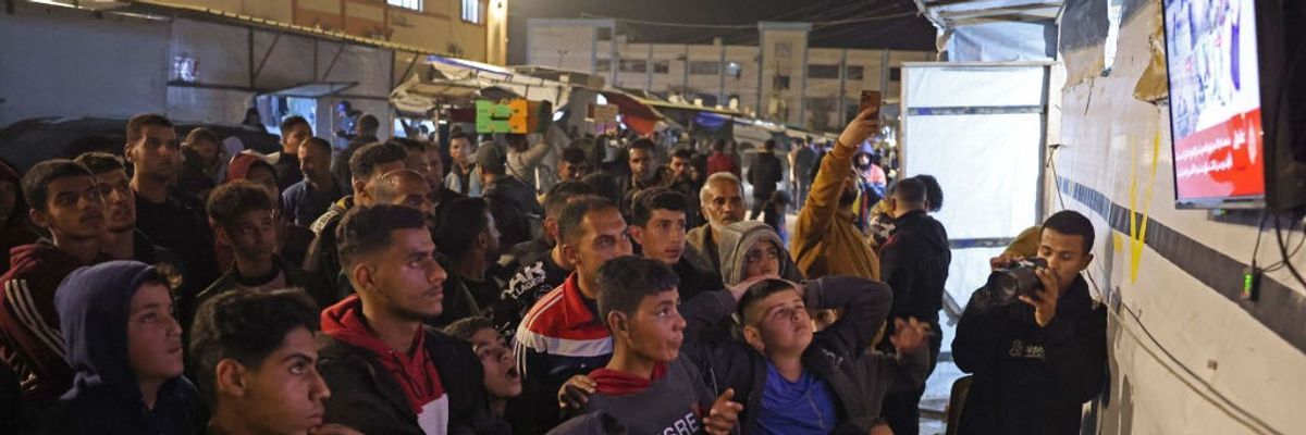 People watch a television in Gaza