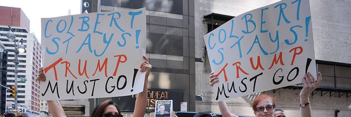 People with signs reading, "Colbert Stays! Trump Must Go!"