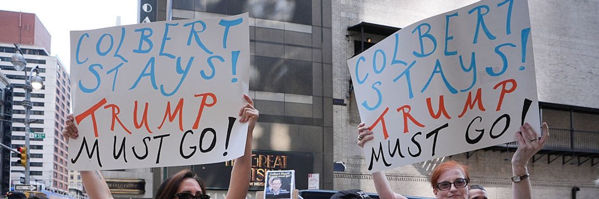 People with signs reading, "Colbert Stays! Trump Must Go!"