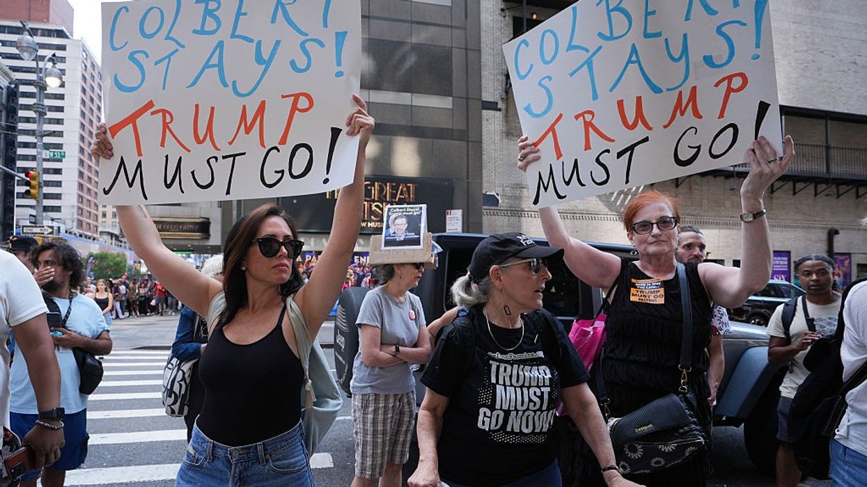 People with signs reading, "Colbert Stays! Trump Must Go!"