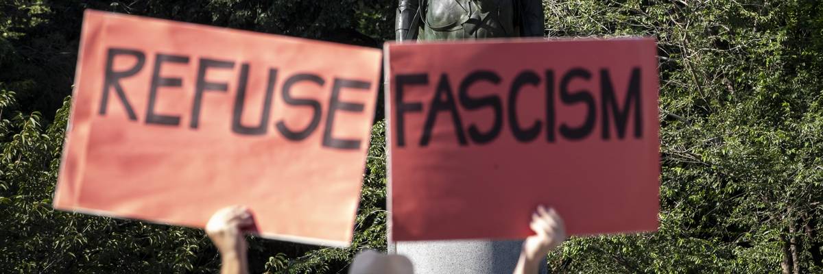 Person carries signs saying, "Refuse fascism."