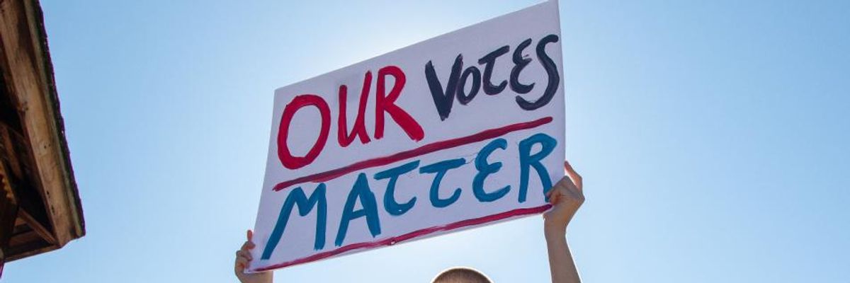 Person holding sign: "OUR VOTE MATTERS"