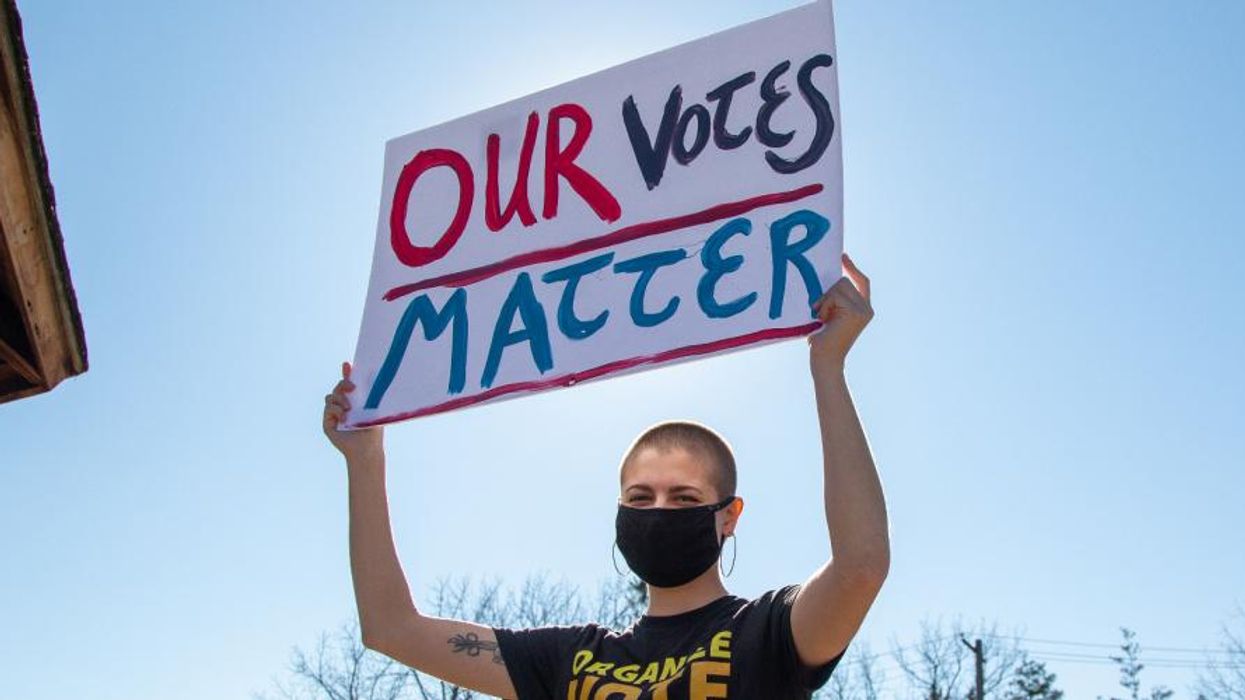Person holding sign: "OUR VOTE MATTERS"