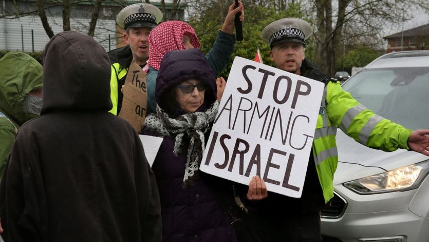 Person holding sign "Stop Arming Israel"