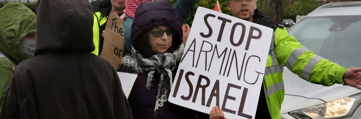 Person holding sign "Stop Arming Israel"
