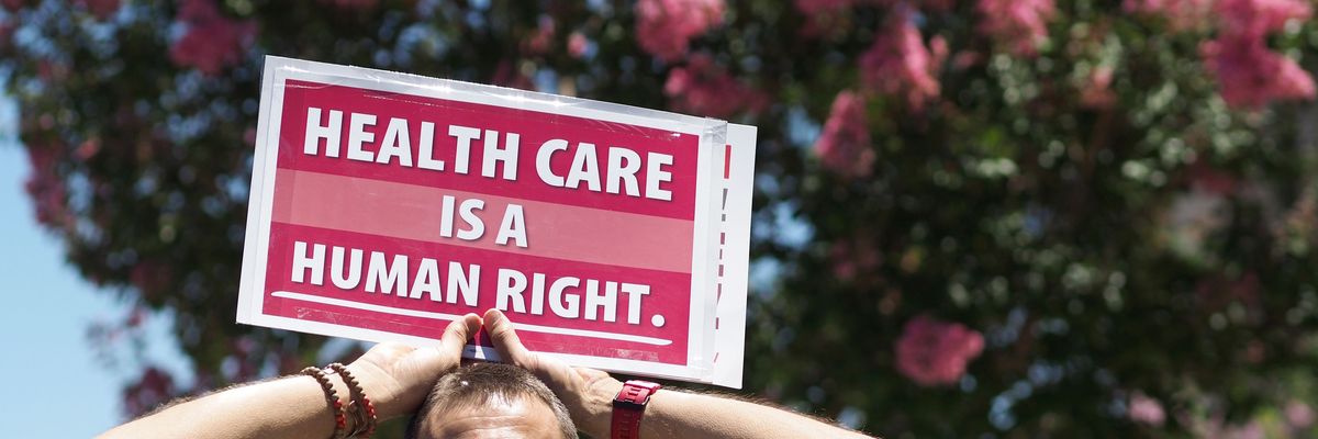 Person holds sign reading, "Healthcare is a human right."
