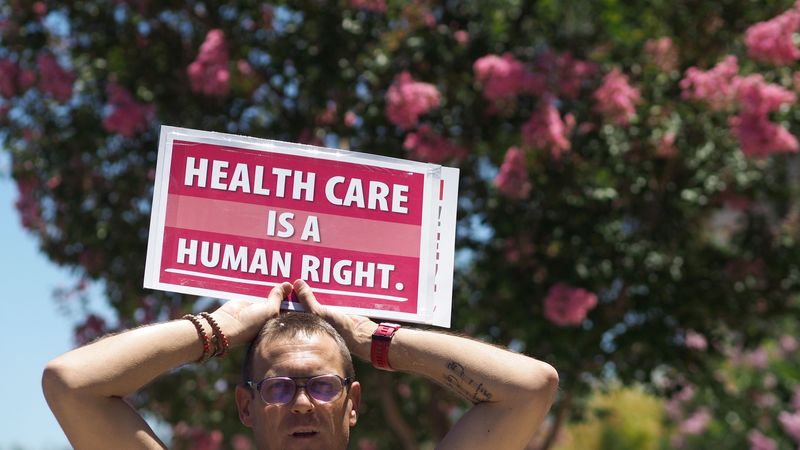 Person holds sign reading, "Healthcare is a human right."
