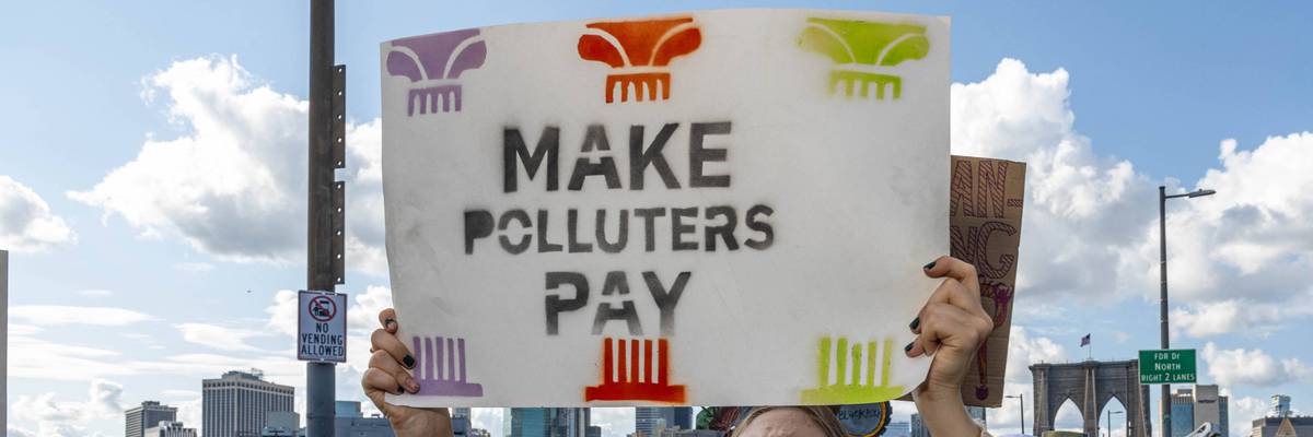 Person holds sign reading, "Make Polluters Pay."