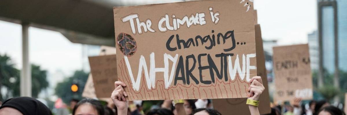 Person holds sign reading, "The climate is changing, why are't we?"