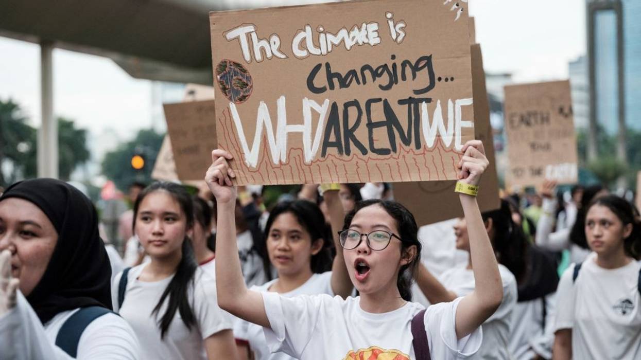 Person holds sign reading, "The climate is changing, why are't we?"