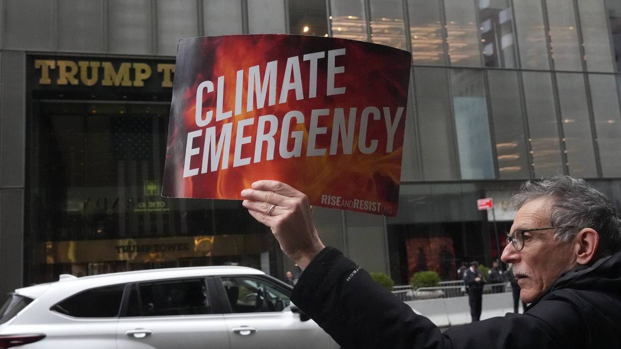 Person holds up "climate emergency" sign outside Trump Tower.