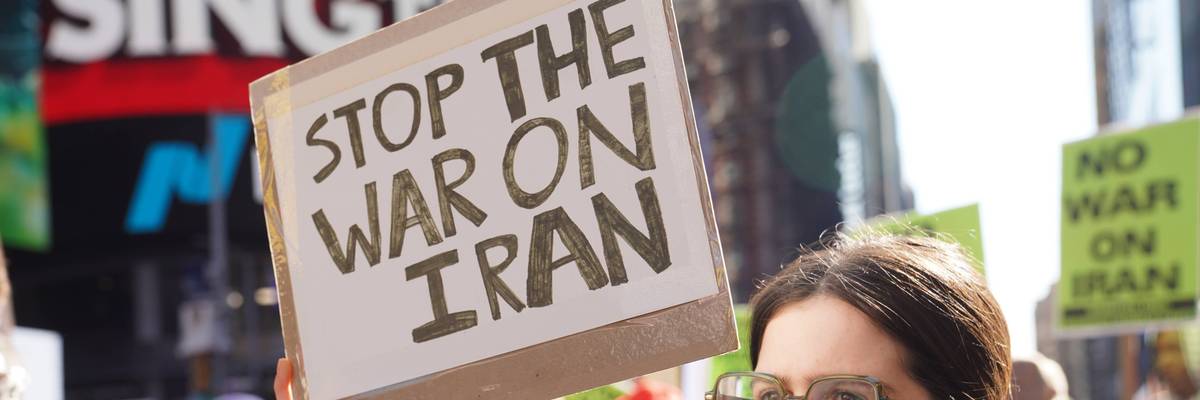 Person holds up sign reading, "Stop the War on Iran."