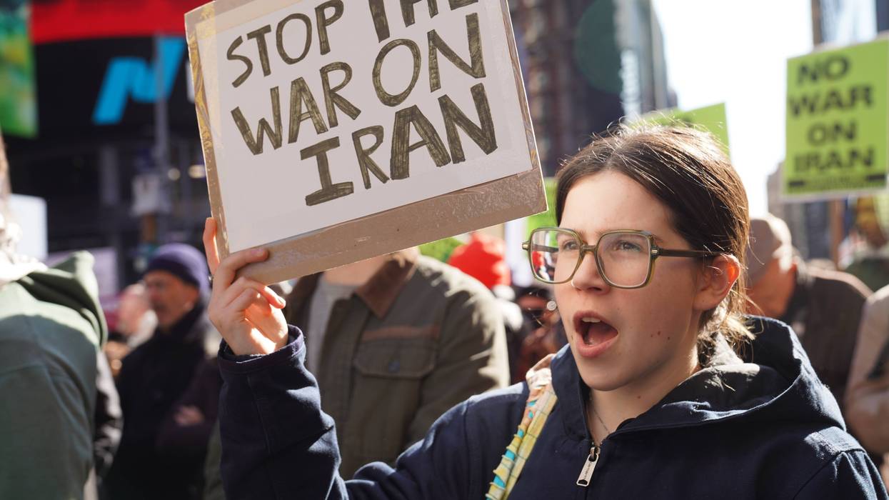 Person holds up sign reading, "Stop the War on Iran."