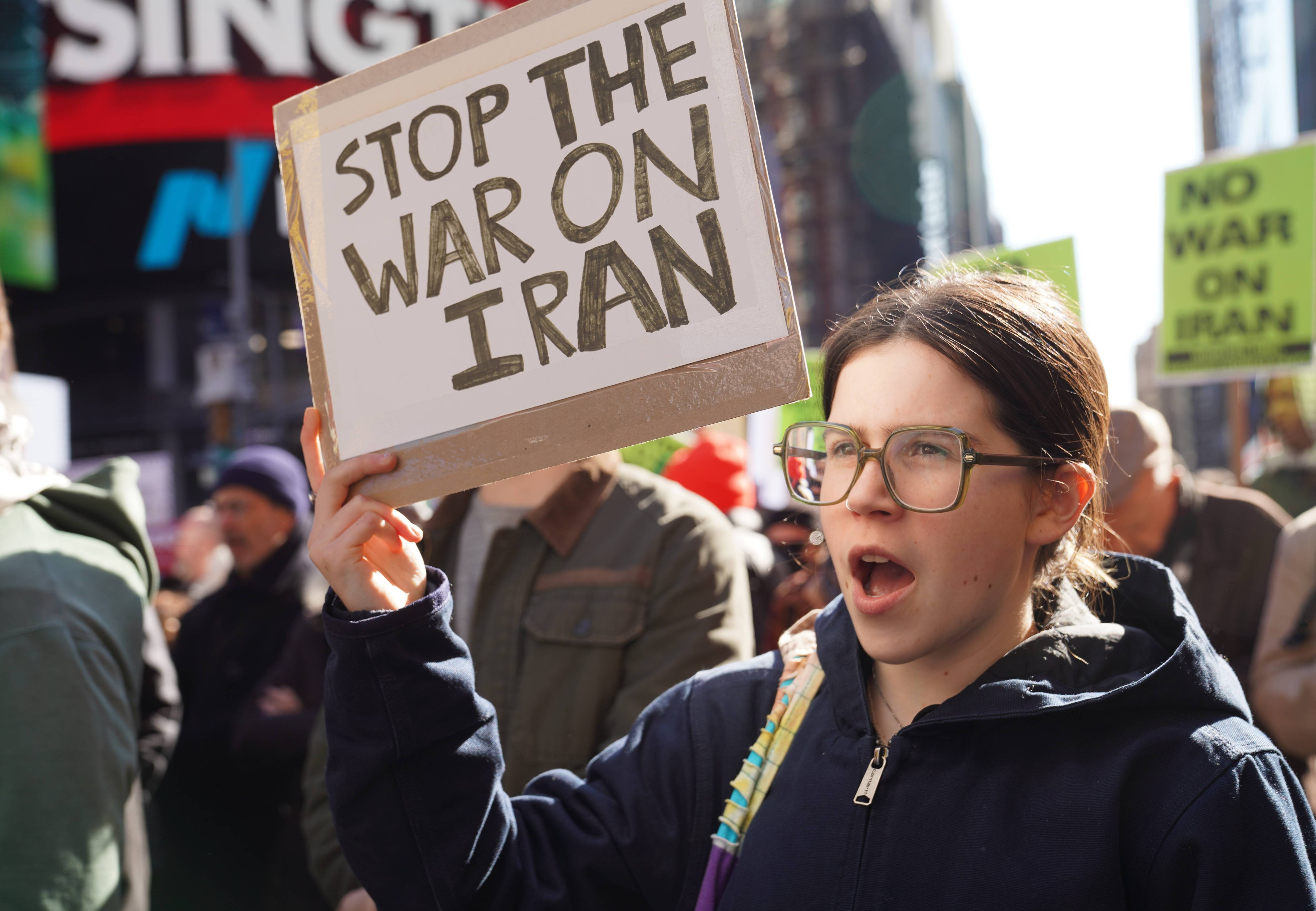Person holds up sign reading, "Stop the War on Iran."