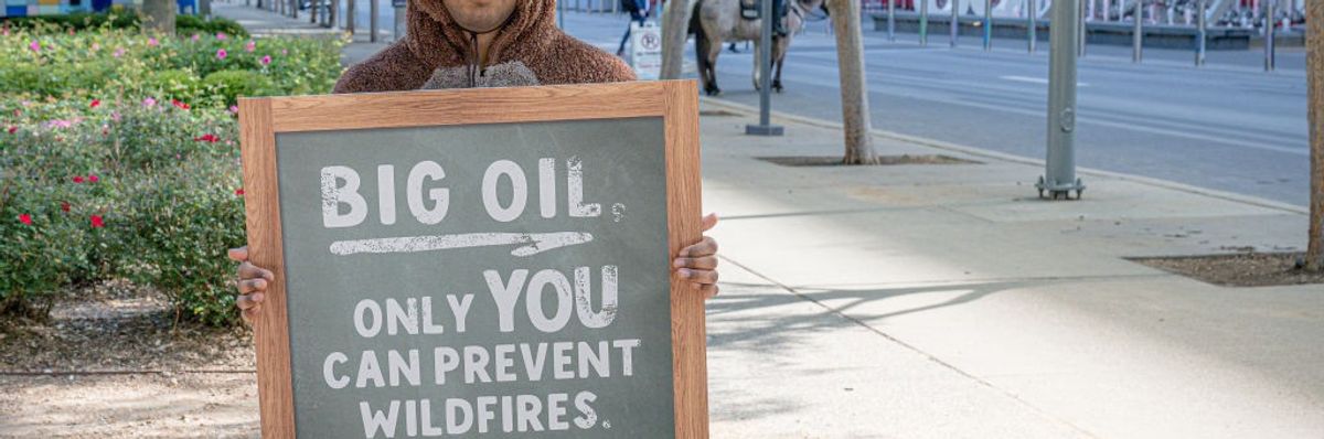 Person in costume holding placard in protest of Big Oil's role in the climate crisis