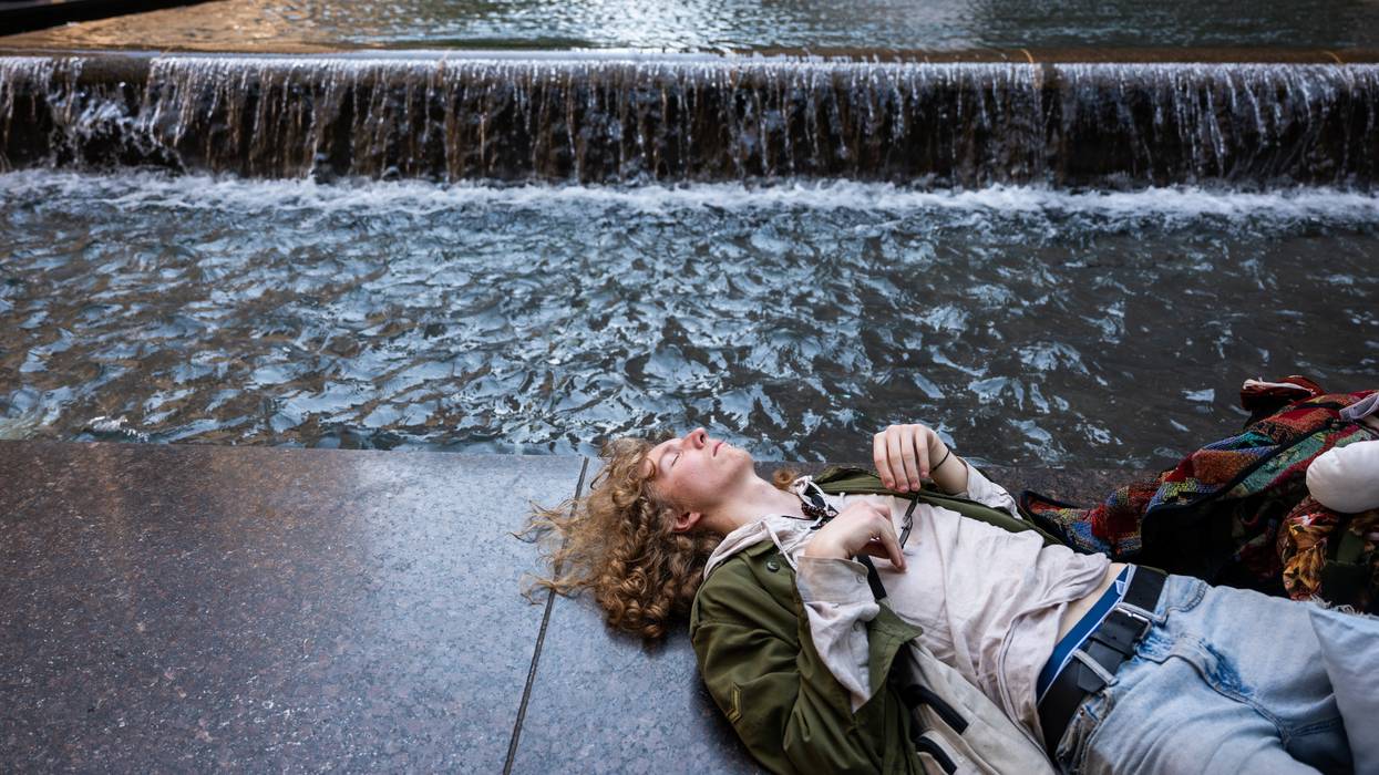 Person rests by fountain during heatwave.