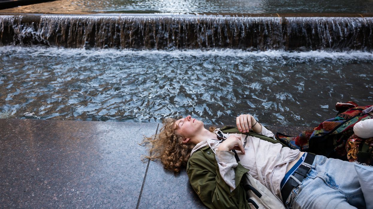 Person rests by fountain during heatwave.