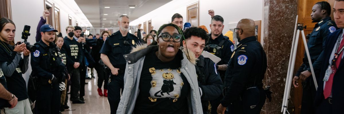 Person shouts as they are forced down a hallway by police.