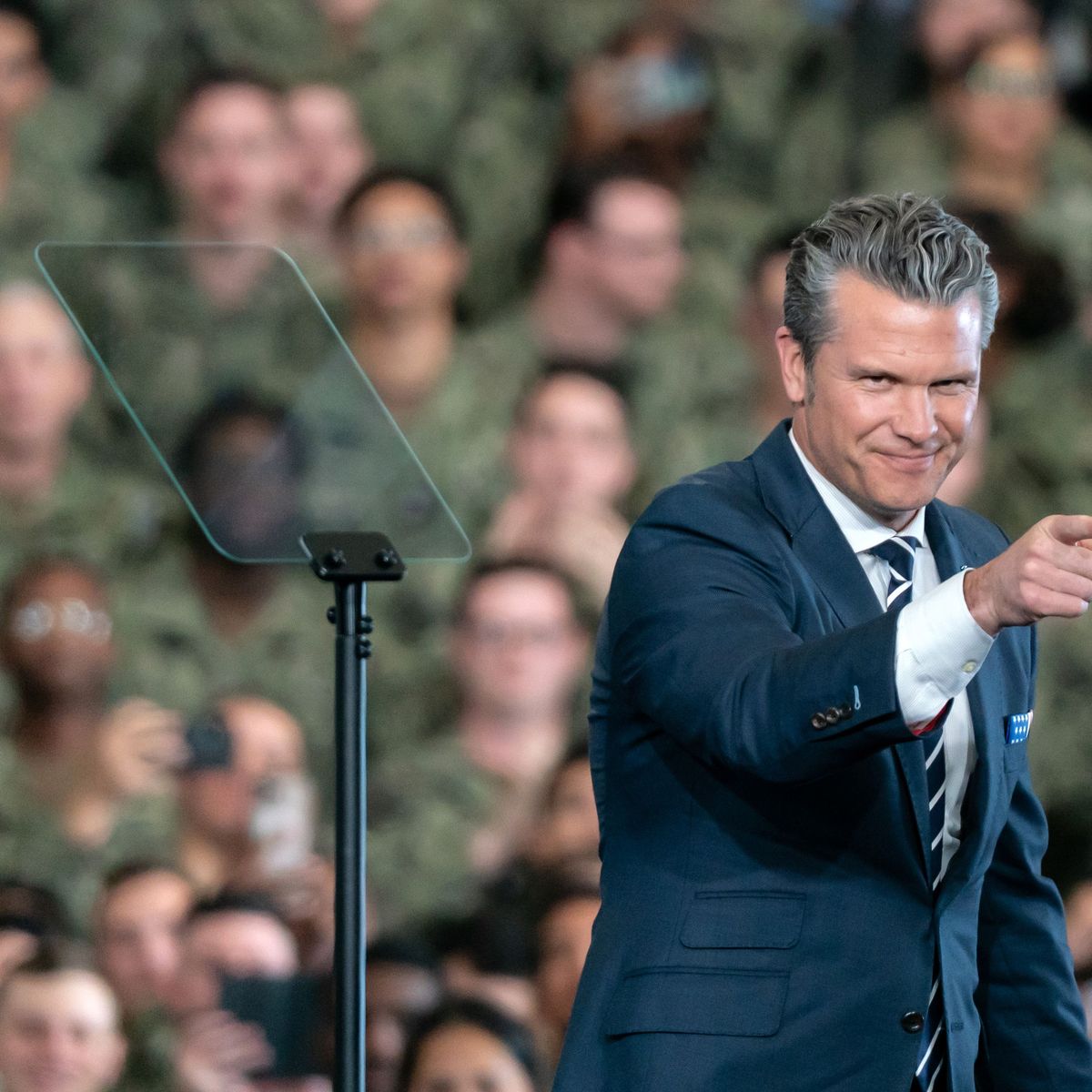 Pete Hegseth points; a crowd of US troops is in the background