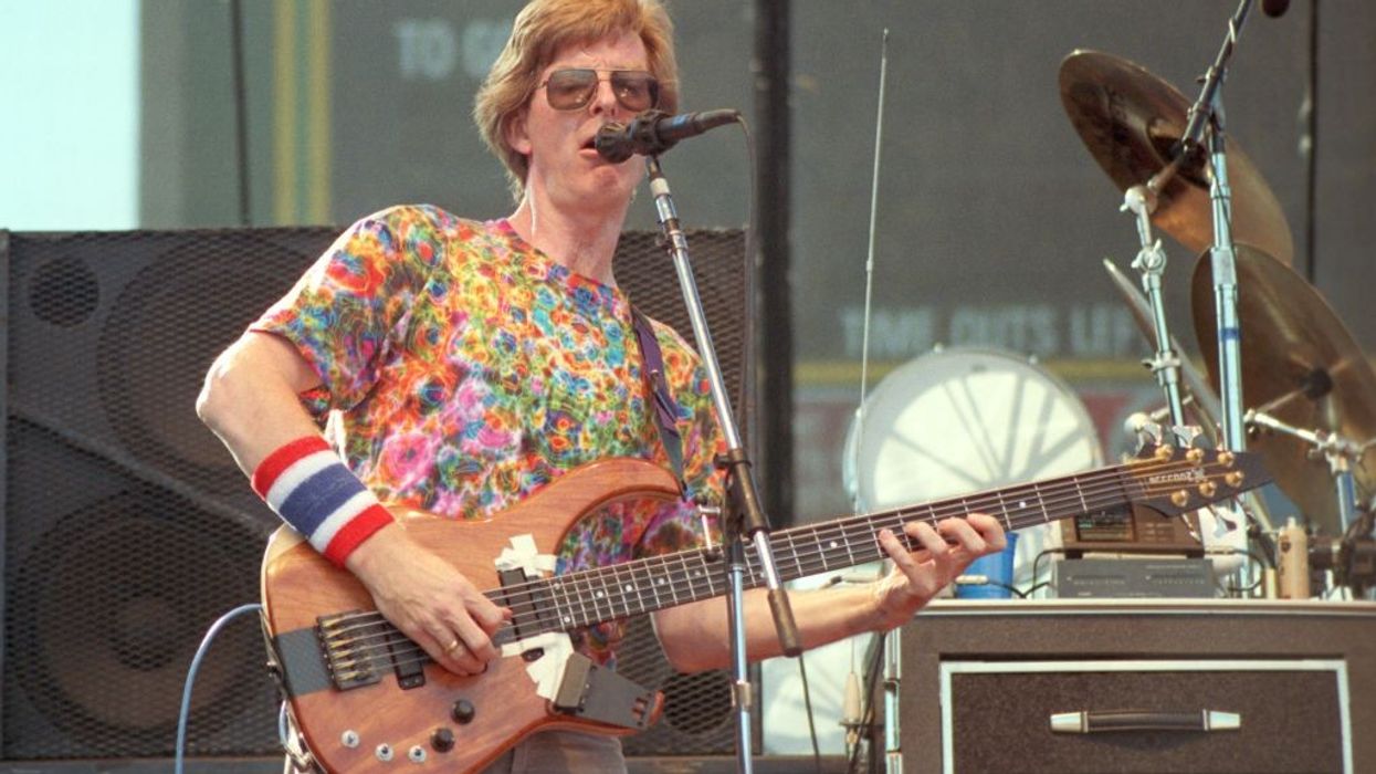 Phil Lesh plays bass wearing a psychedelic t-shirt, sunglasses, and red-white-and-blue wristband