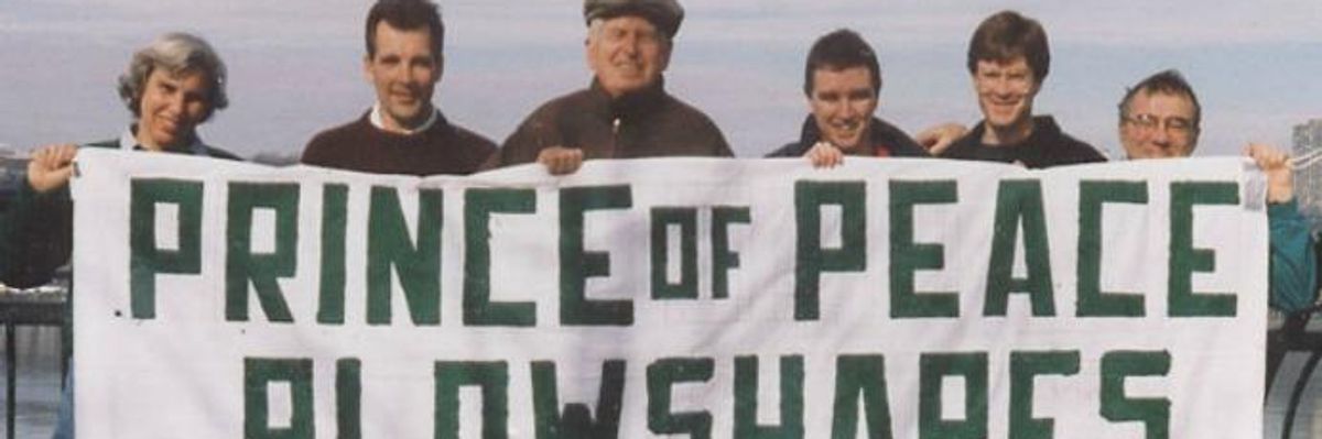 Philip Berrigan and other activists hold up a banner for the Plowshares Movement. 