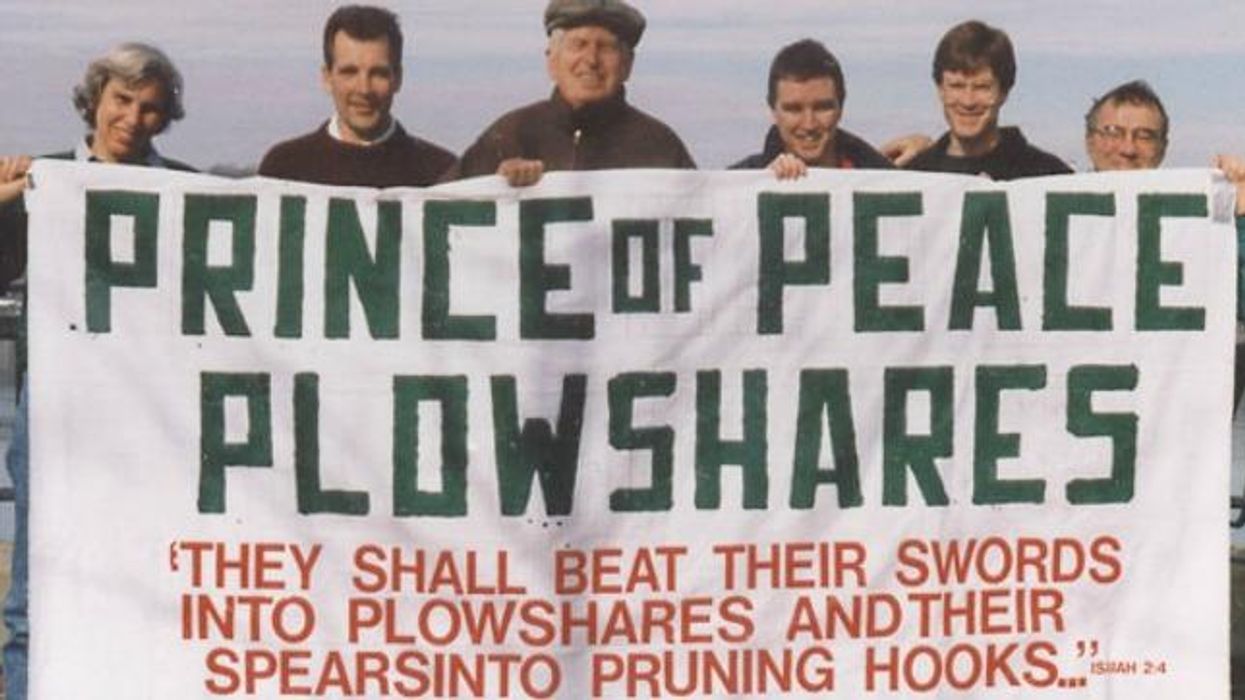 Philip Berrigan and other activists hold up a banner for the Plowshares Movement.