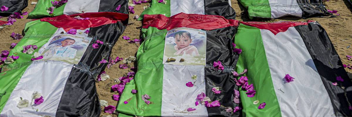 Photographs rest on bodies wrapped in Palestinian flags