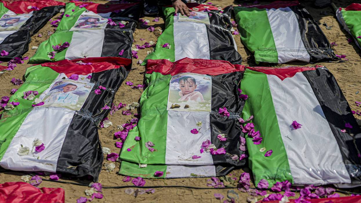Photographs rest on bodies wrapped in Palestinian flags