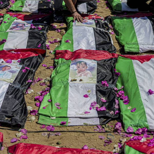 Photographs rest on bodies wrapped in Palestinian flags