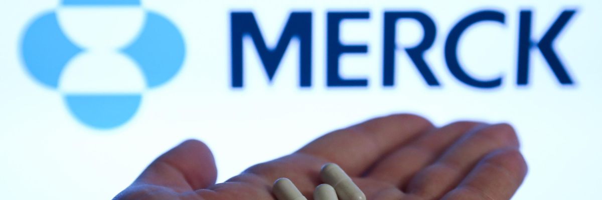 Pills are seen with Merck logo displayed on a screen in the background
