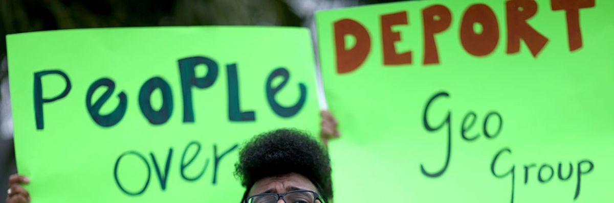 placards at a protest against Geo Group