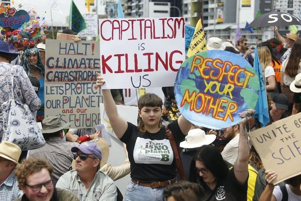 Placards at an environmental protest, one of which reads 'capitalism is killing us'