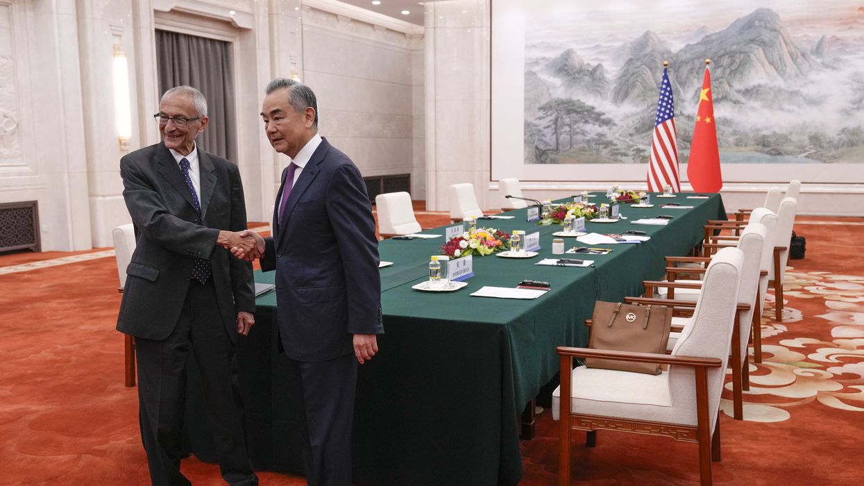 Podesta and Yi shake hands.