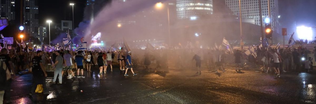 Police spray water cannons at protesters in Israel at night.