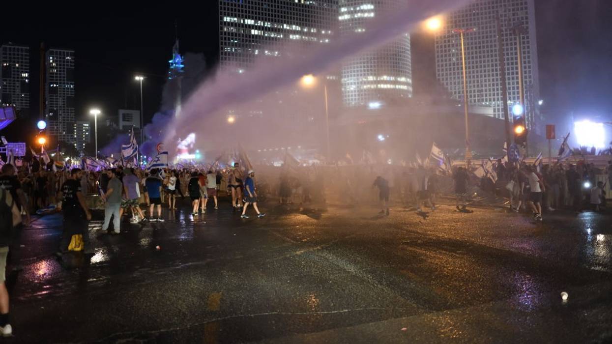 Police spray water cannons at protesters in Israel at night.