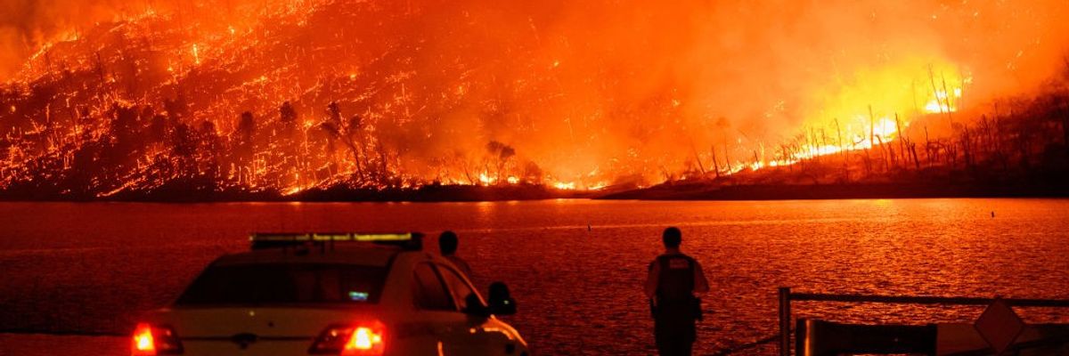 Police watch as a massive wildfire burns over Lake Oroville in California