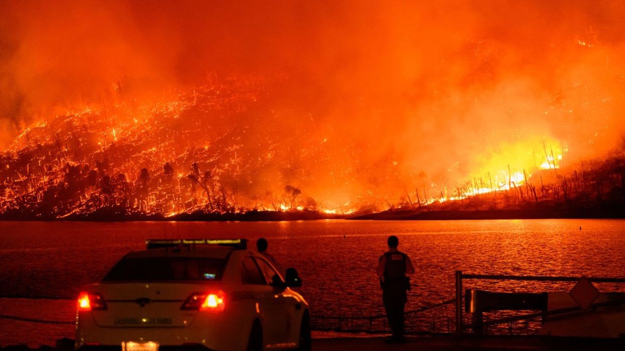 Police watch as a massive wildfire burns over Lake Oroville in California